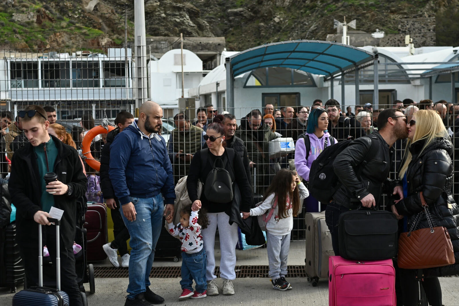 People wait on the quayside to embark a ferry at the port on the Greek 