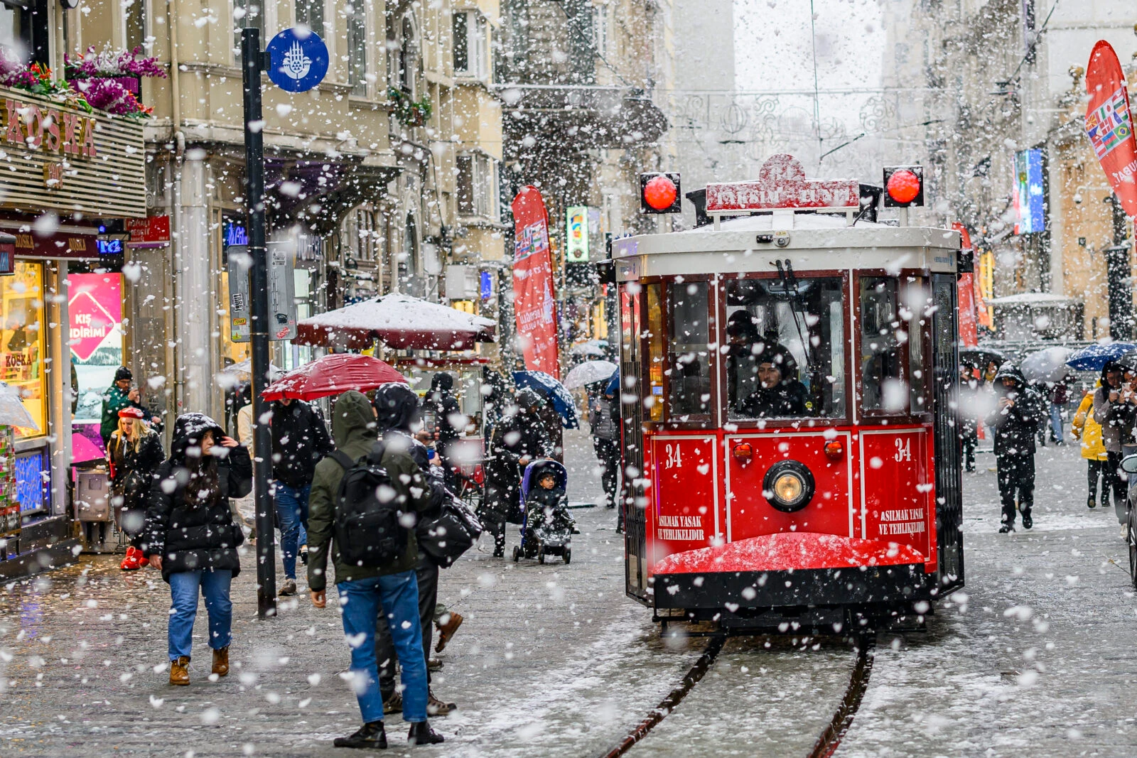 People walking on Istiklal Avenue in Istanbul as snow falls on February 19, 2025.