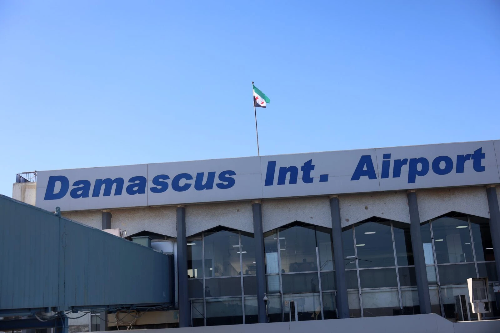 The three-star opposition flag flutters over the Damascus International Airport after it was reopened