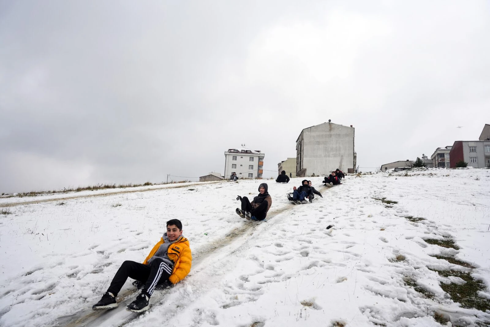 kids sliding down slopes on plastic bags in snow covered istanbul