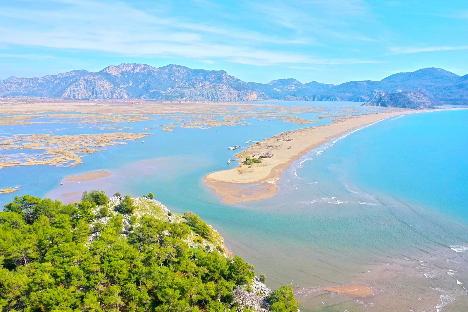 An aerial photograph showcasing the stunning İztuzu Beach in Muğla, Türkiye, where golden sands meet the turquoise waters of the Mediterranean.