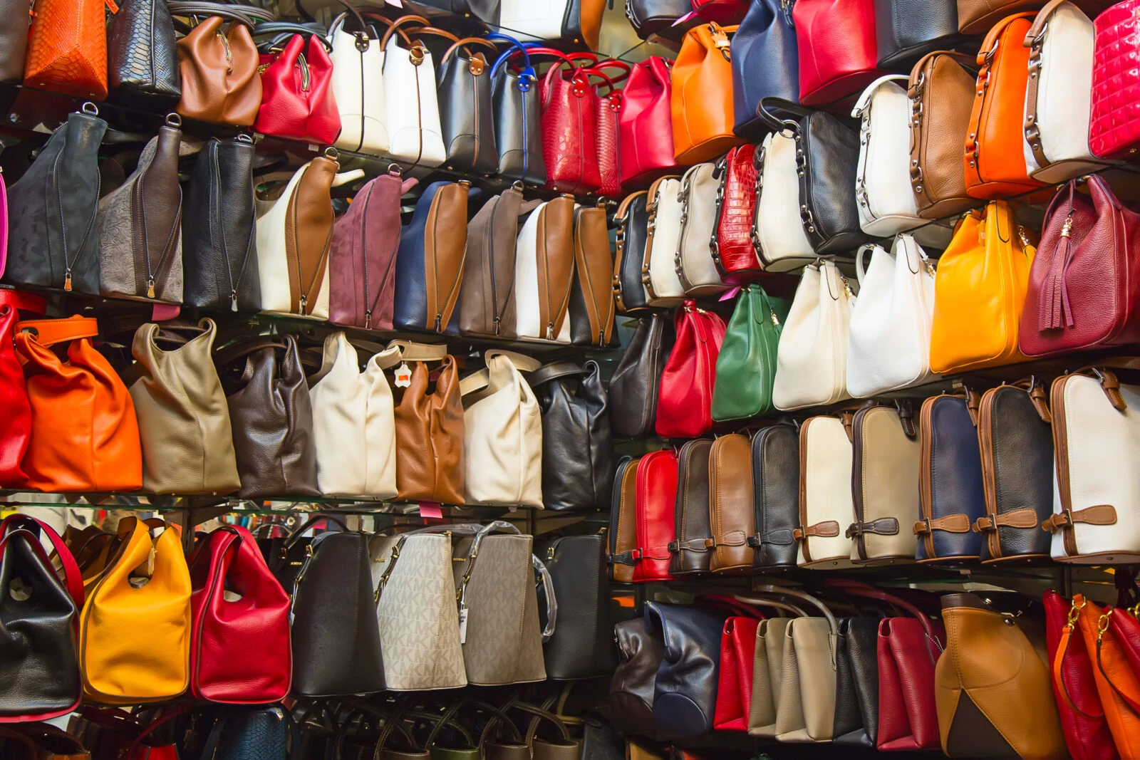 Replica designer bags displayed for sale on a bustling narrow street near Istanbul's Grand Bazaar, a hub for counterfeit fashion items.