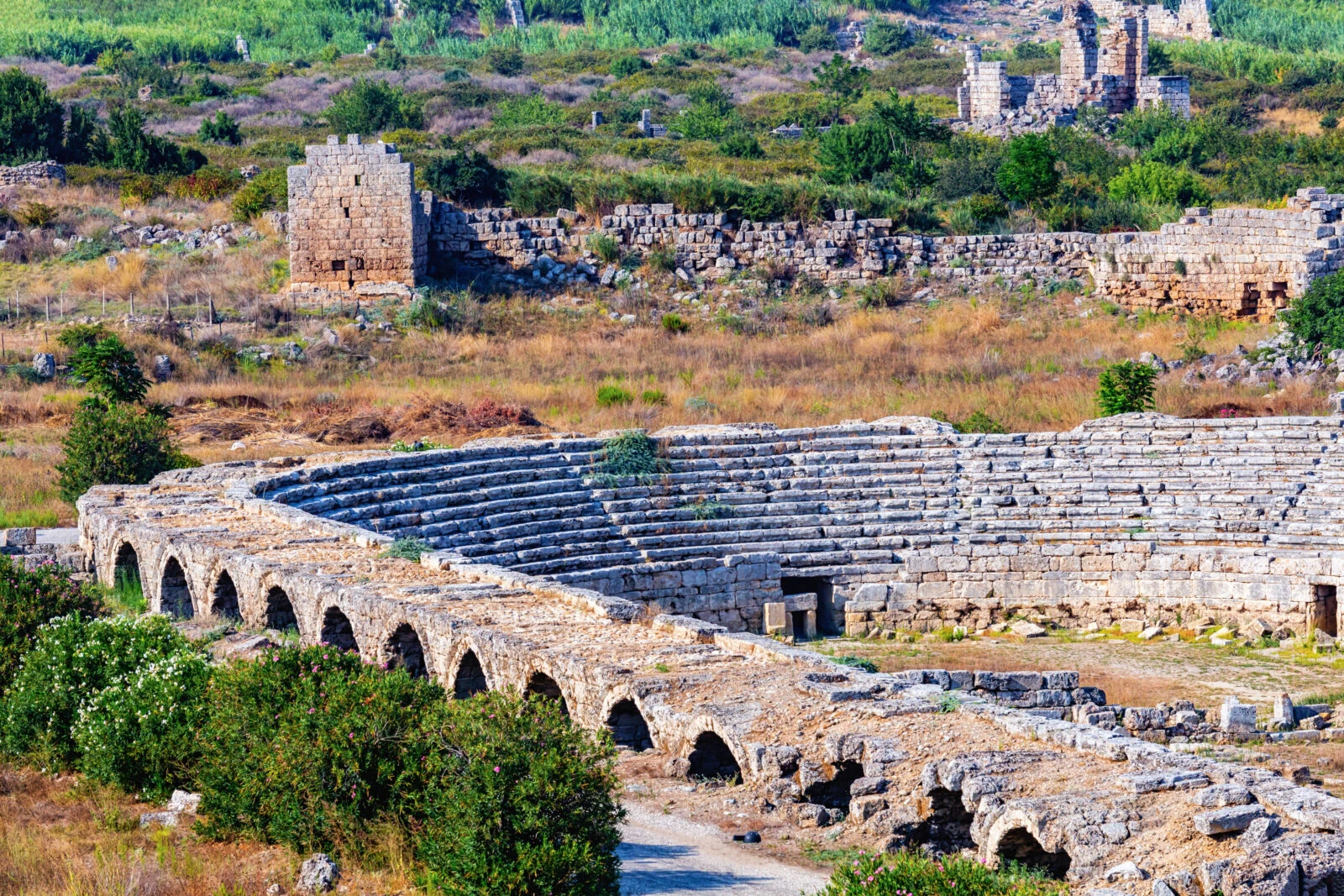 The ancient Perge Stadium in Antalya, Türkiye, featuring arched walls and tiered seating.