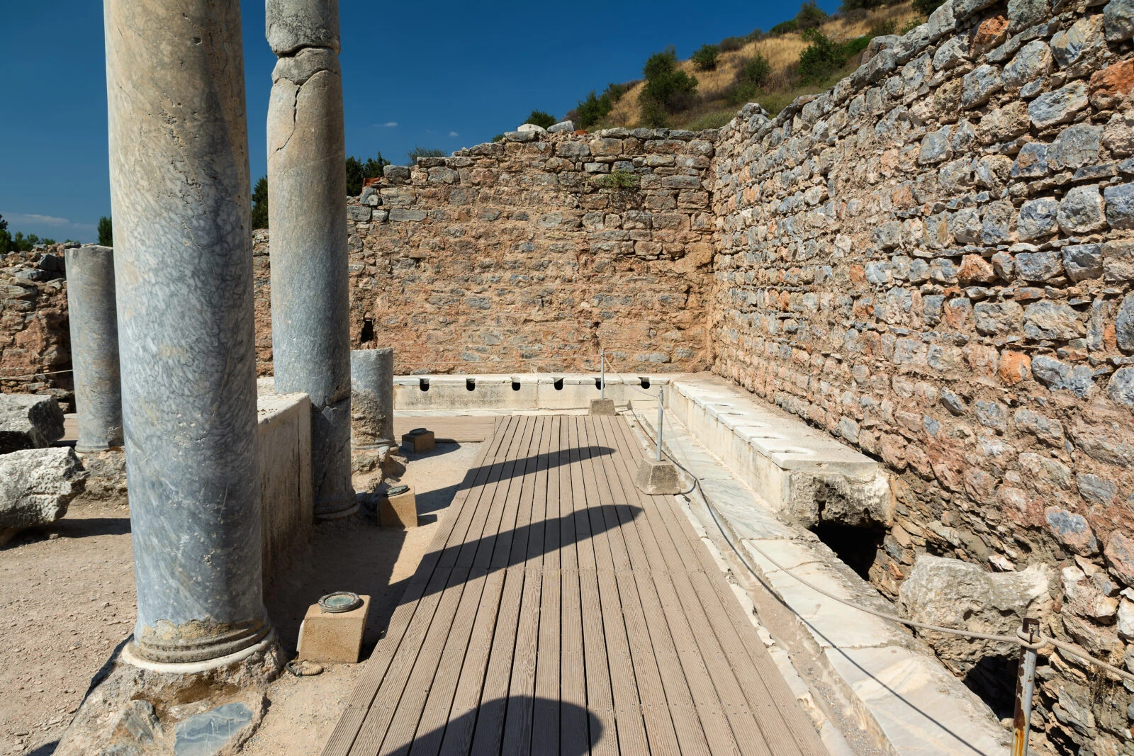 A photo showing the ancient public latrines in Ephesus, showcasing the historical significance of the public sanitation system in İzmir, Türkiye.