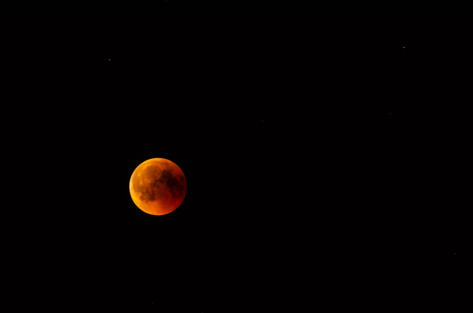 A deep red blood moon glowing against the dark sky during a total lunar eclipse.