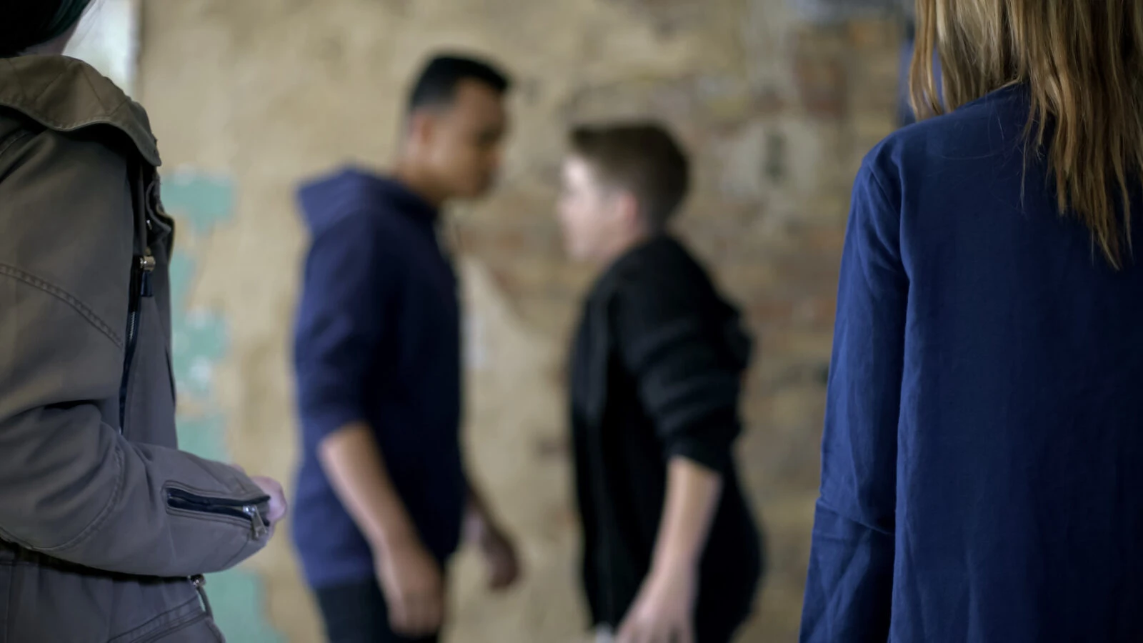 A group of teenage boys involved in a fight, displaying bullying and self-defense actions, with a blurred background emphasizing movement and intensity.