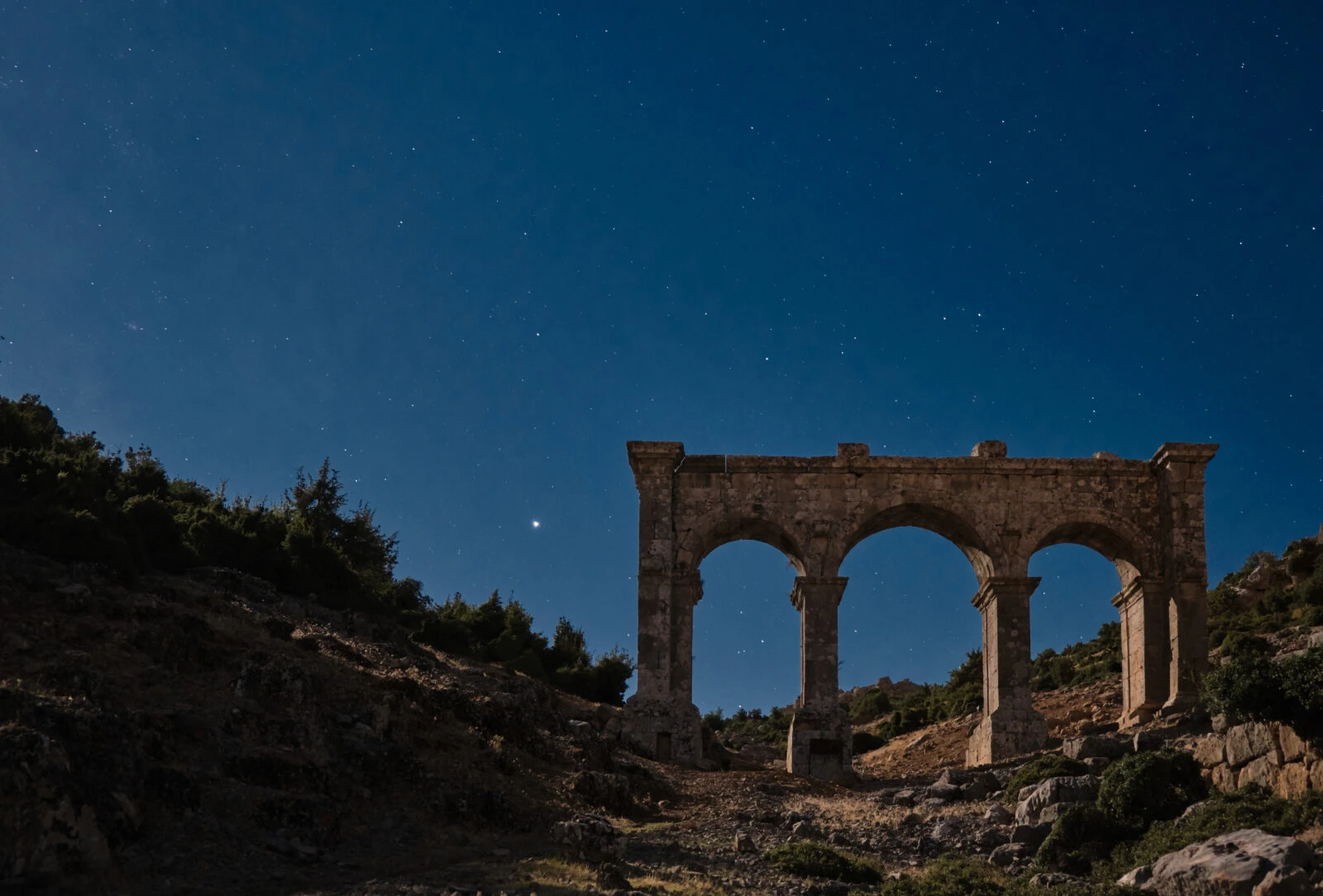 A night view of ancient stone arches under a starry sky, ideal for stargazing.