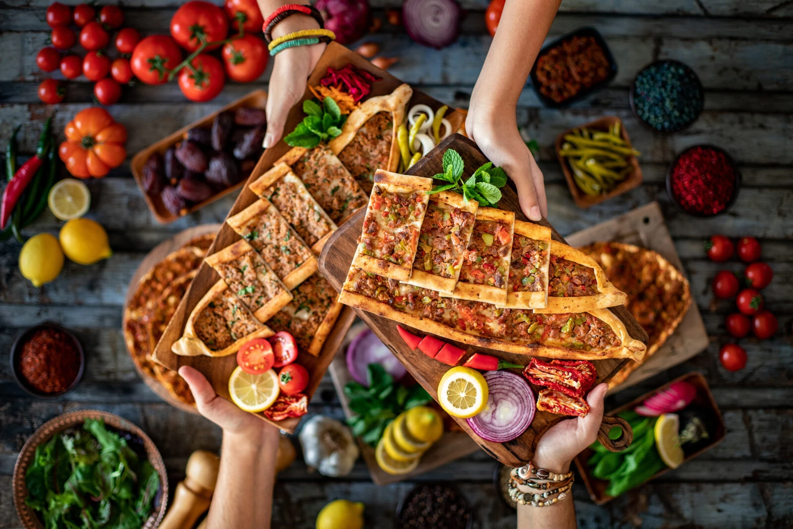 A variety of traditional Turkish dishes, including lahmacun, minced meat pide (kiymali), and cubed meat pide (kusbasili), served on a platter.