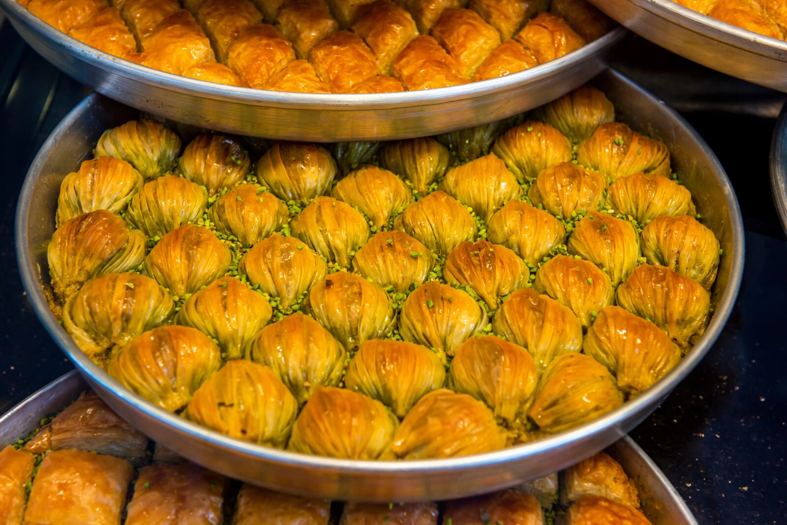 Turkish cuisine - A close-up shot of Mussel Baklava on a tray, showcasing its unique shape and pistachio filling. A traditional dessert from Gaziantep, Türkiye.