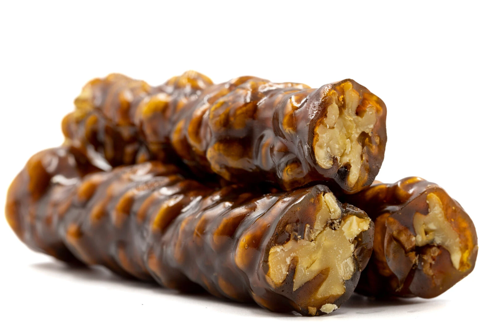 Close-up of Sucuk Lokum, a Turkish dessert with walnuts coated in fruit molasses, arranged in a stack.