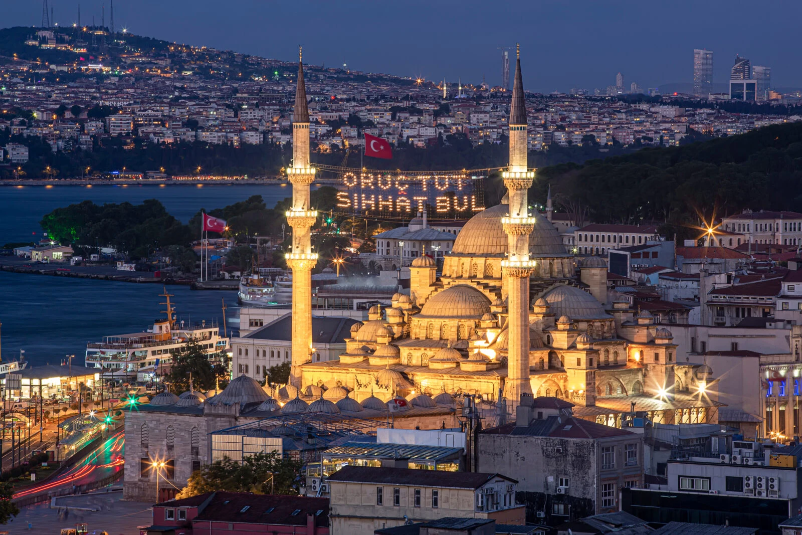 Aerial view of the New Mosque in Istanbul at night, with Ramadan messages glowing between its minarets.