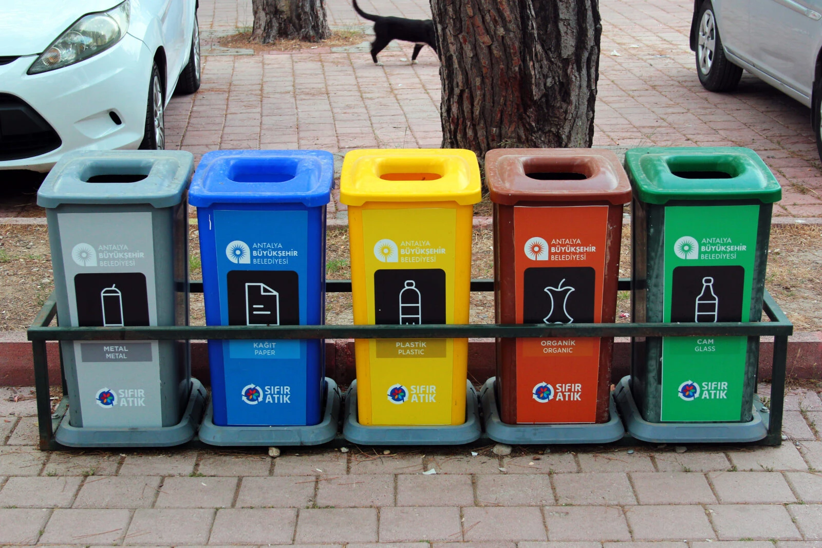 Five color-coded garbage bins for recyclable waste at Sarisu Beach, Antalya, Türkiye.