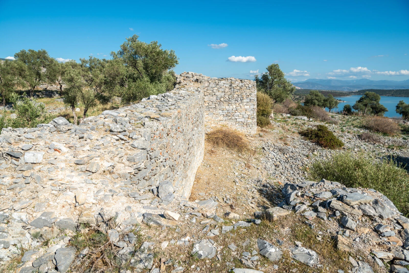 A section of the ruined acropolis wall, later repurposed as a fortress, at the ancient city of Iasos in Muğla, Türkiye, standing against a clear blue sky.