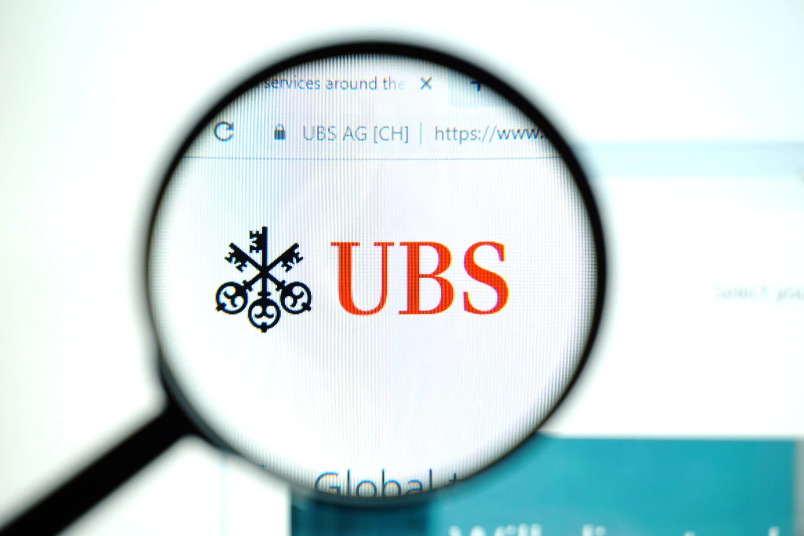 a magnifying glass focusing on the UBS logo displayed on a computer screen