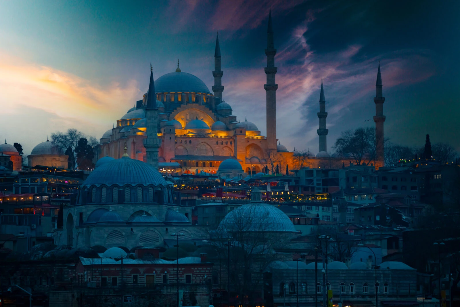 Dusk over Suleymaniye Mosque in Istanbul, with dramatic clouds and warm golden lights highlighting its silhouette.