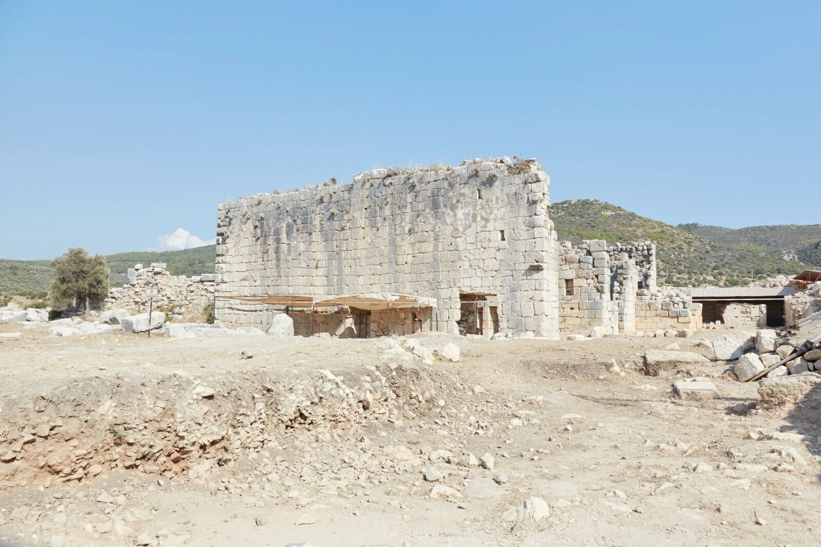 An archaeological excavation site in the ancient city of Patara, Antalya, Türkiye, with ruins and excavation tools visible.