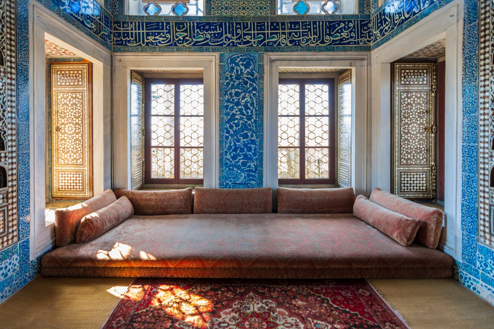 The ornate interior of the Baghdad Pavilion in Topkapi Palace, Istanbul, showcasing intricate tilework, stained glass windows, and historical Ottoman architecture.