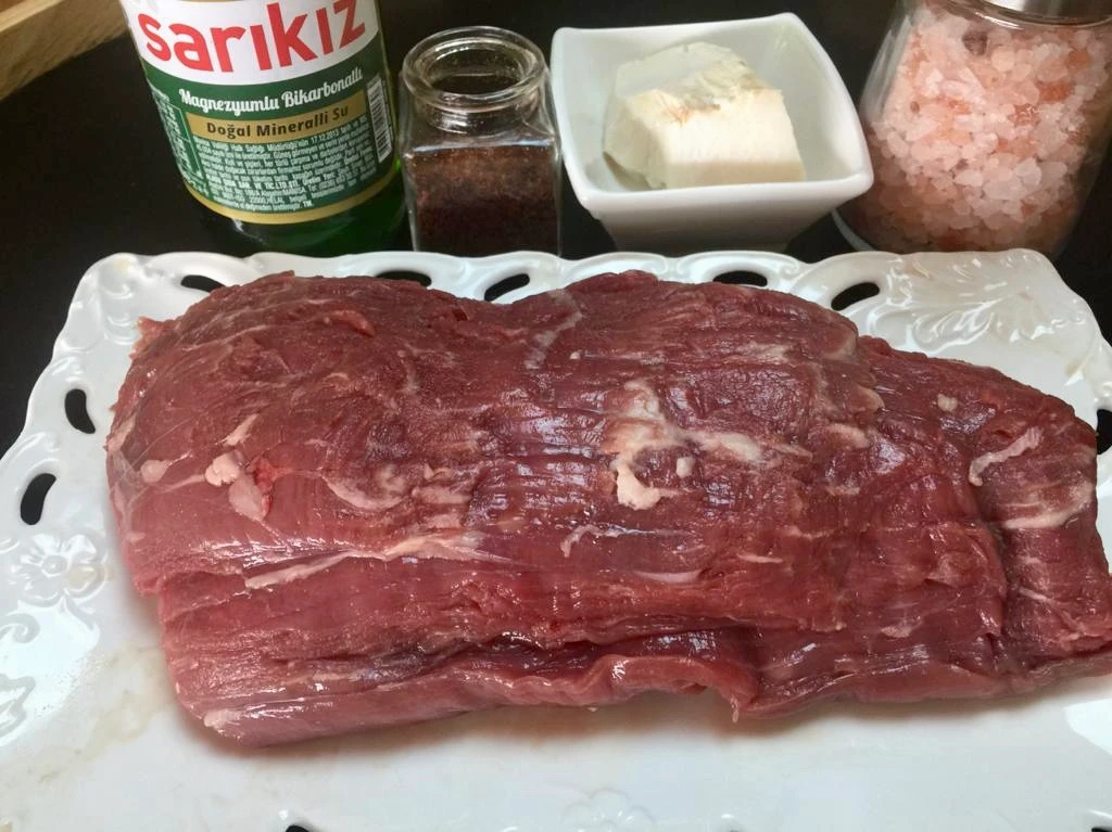 A raw beef cut placed on a white board, ready for doner kebab preparation.