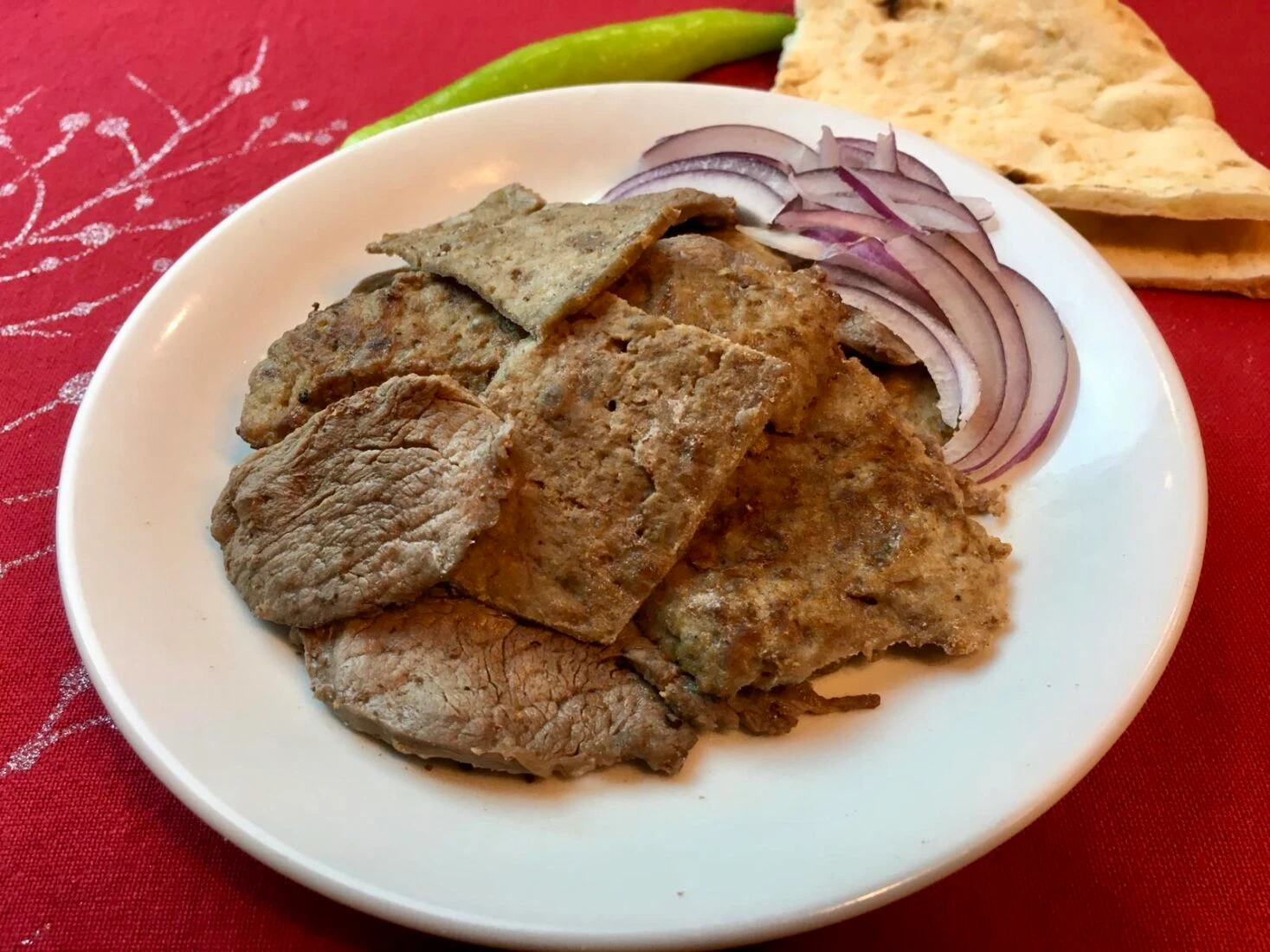 A plate of homemade doner kebab with onions on the side.