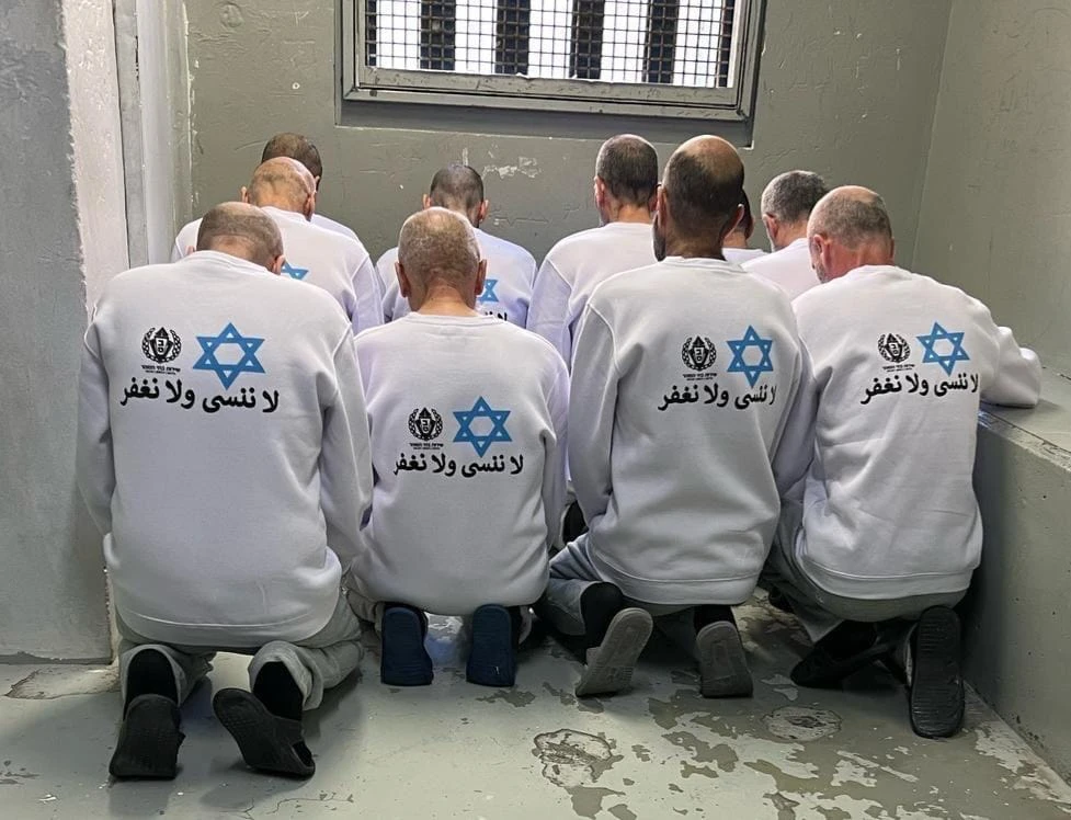 Prisoners wear uniforms with the Star of David and the Arabic phrase "We will not forget, we will not forgive"