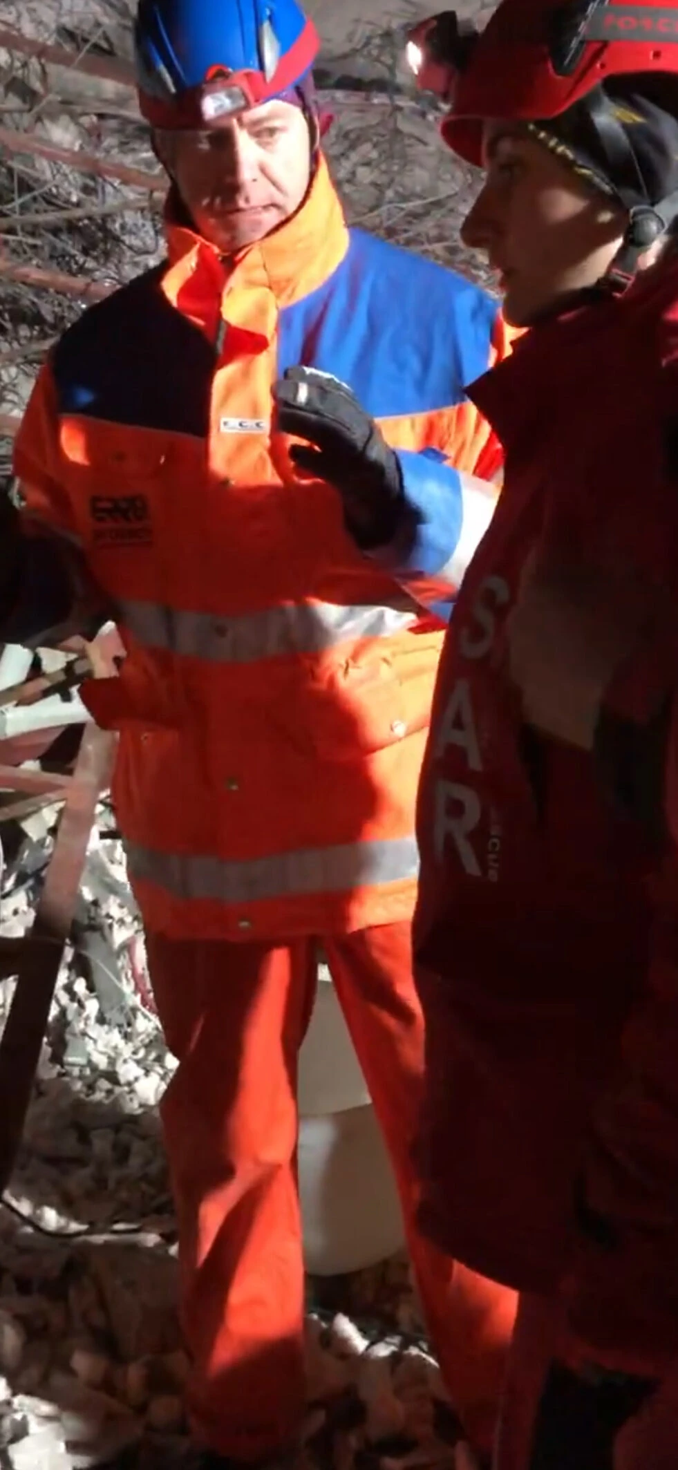 A Dutch and Turkish search-and-rescue worker discuss their approach while wearing protective helmets