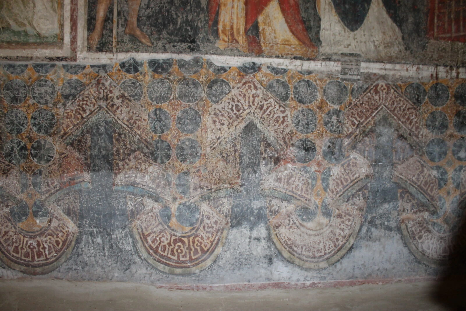 Textile folds with pseudo-Arabic inscriptions on the lower border of a fresco in the Church of S. Antonio, Ferrara, Italy.