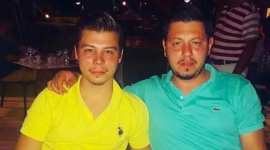 Cemal Metin Avci and his brother, Mertcan Avci, seated at a table in a casual setting, wearing polo shirts