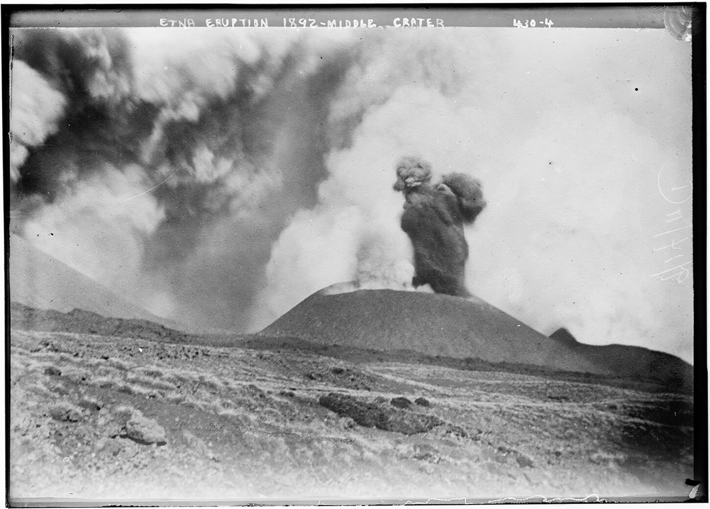 A historical black-and-white photograph capturing the 1892 eruption of Mount Etna’s middle crater, with smoke and ash billowing into the sky.