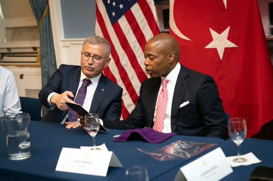 Photo shows NYC Mayor Eric adams looking at a document in Turkish mayor's hand