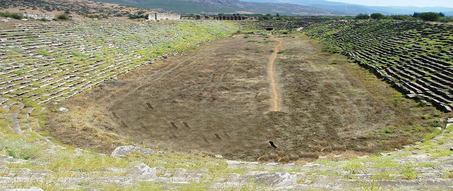 The remains of Ephesus Stadium in Izmir, Türkiye, with stone terraces and arched ruins.