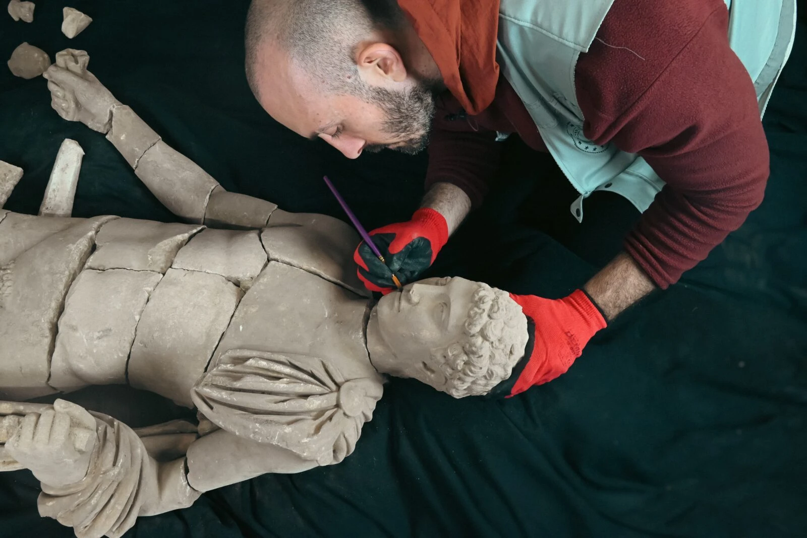 Fragmented statue of Hermes being reassembled at an excavation site.