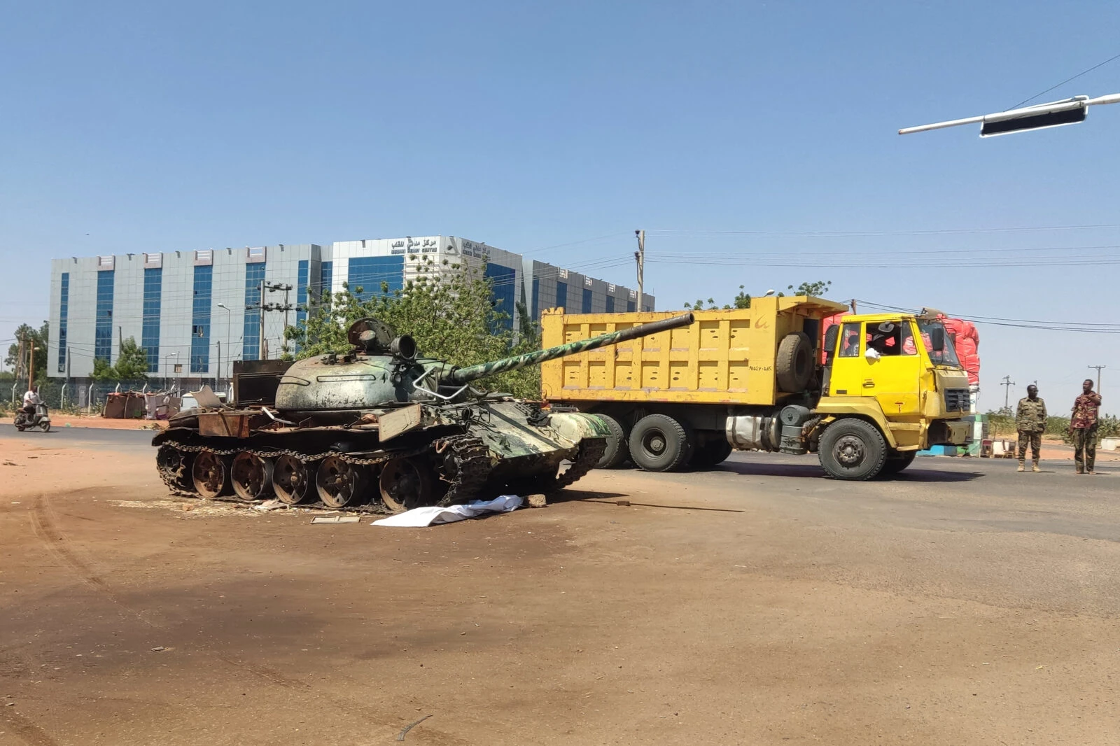 photo shows A truck driving past a Sudanese army tank at the entrance of Wad Madani