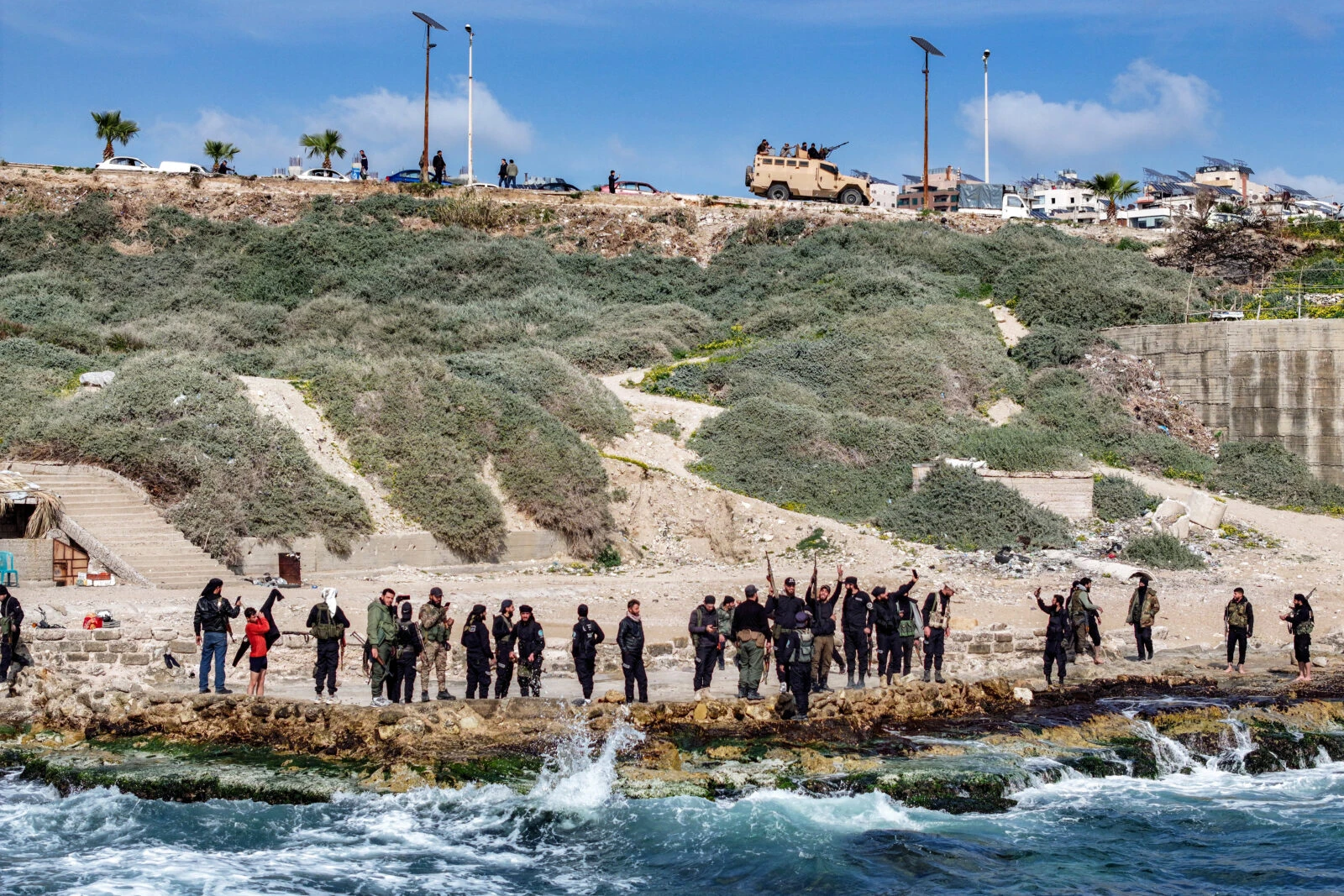 Photo shows members of security forces loyal to the interim Syrian government standing along a rocky beaech by Mediterranean sea coast.