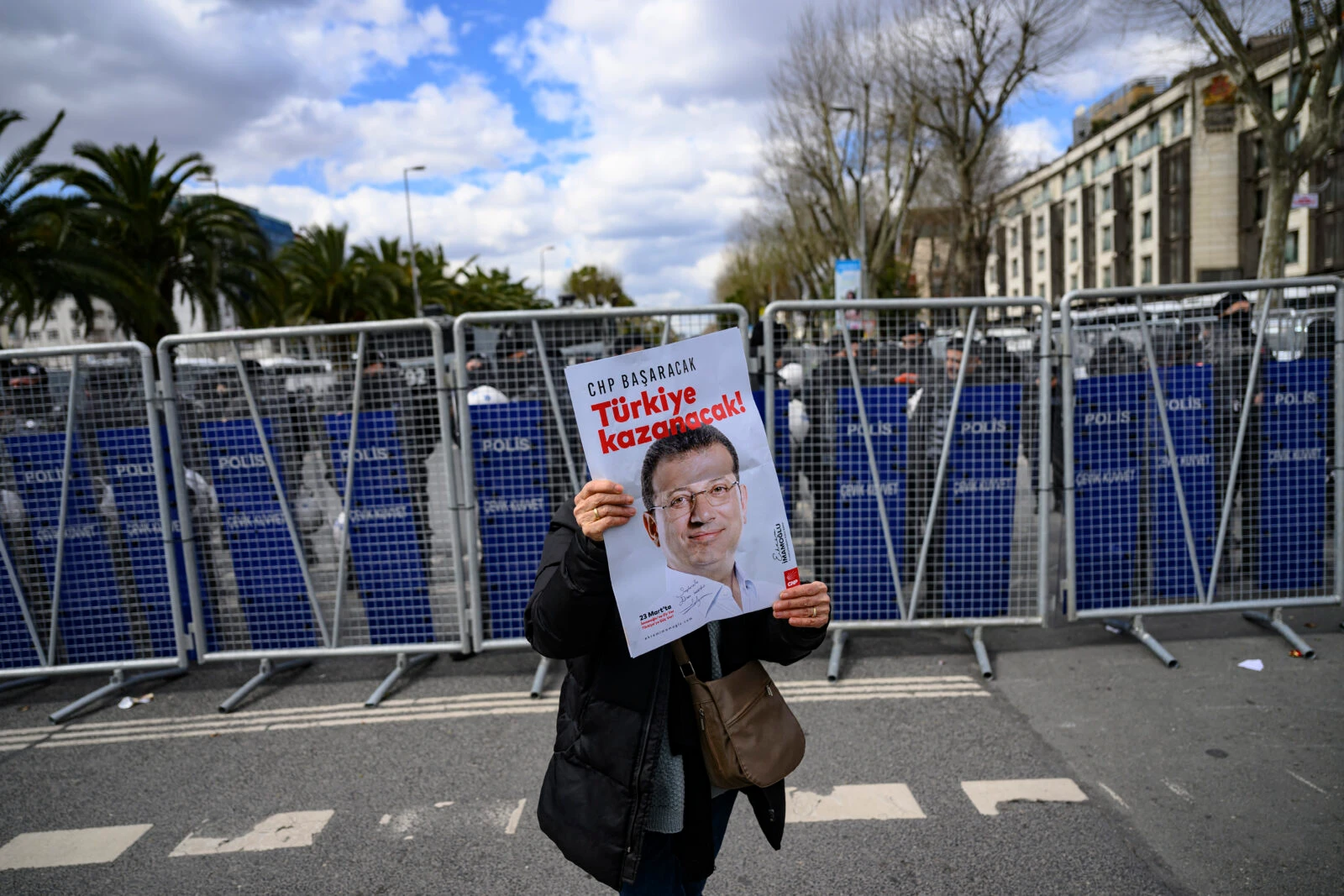 Photo shows supporters of Istanbul Mayor holding a banner as they demonstrate in front of the Turkish police barricade.