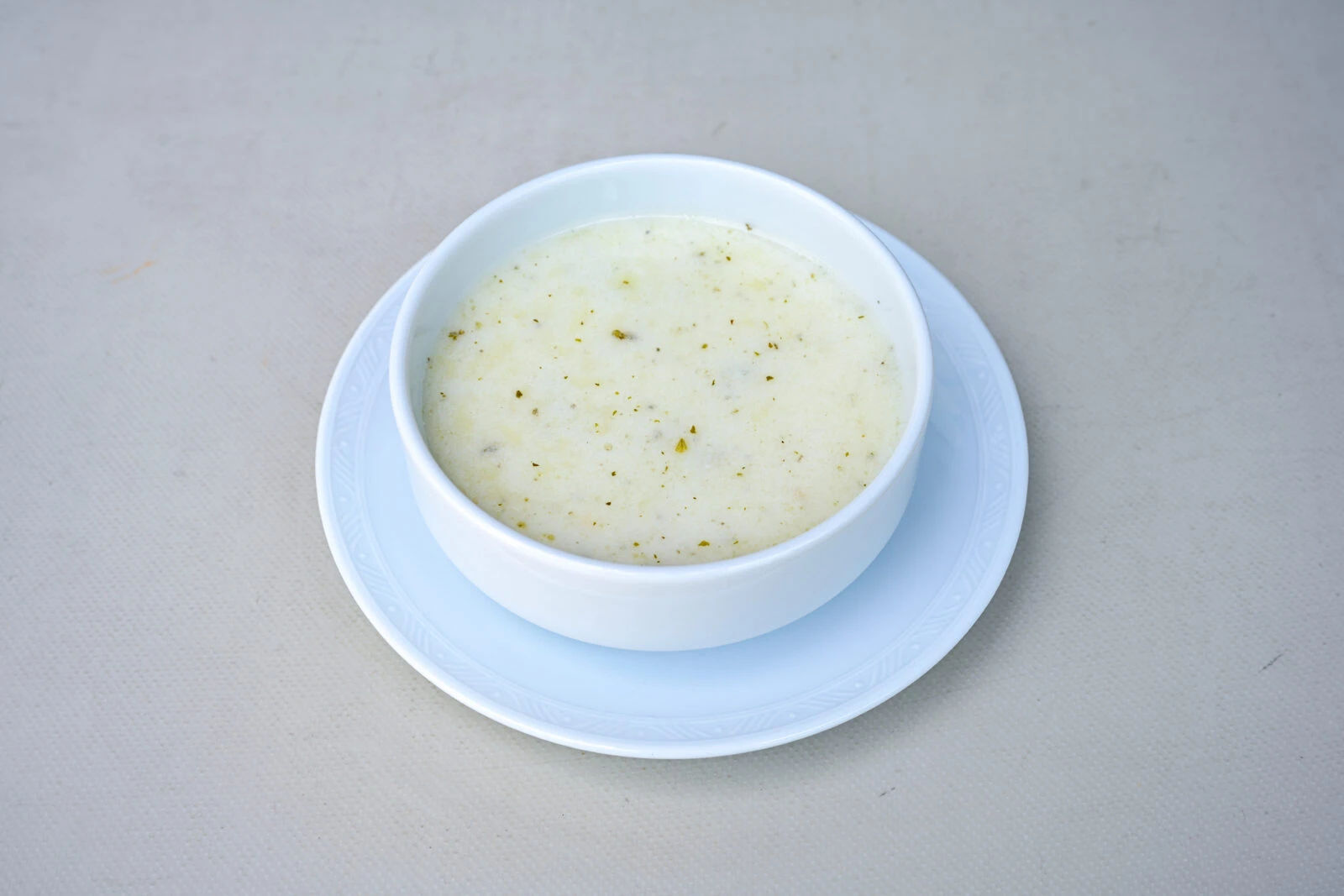 Nohutlu yayla corbasi, a creamy Turkish soup made with yogurt, chickpeas, and herbs, served in a white bowl.