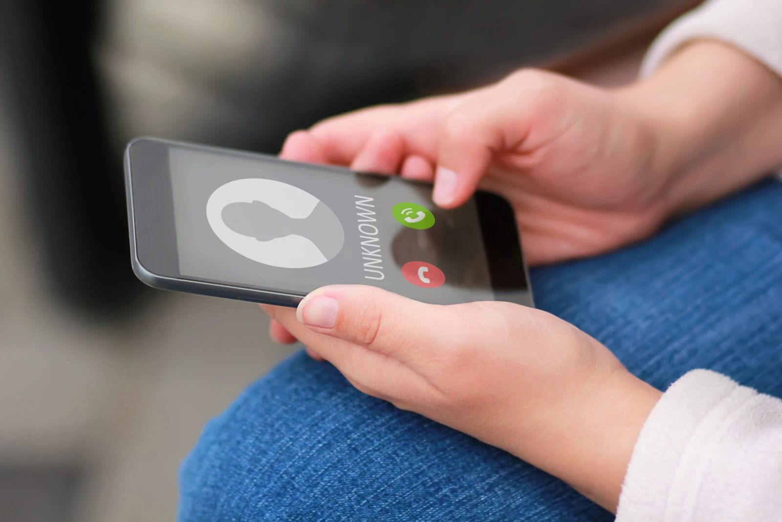 Close up of woman's hands with smartphone and unknown incoming phone call on it, fraud or scam schemes