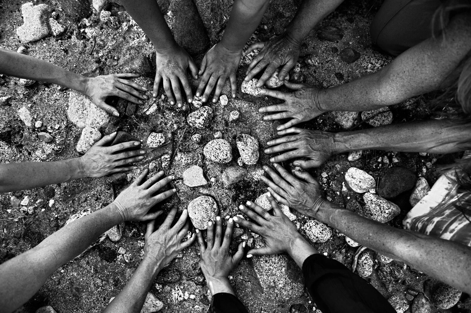 Close-up of women's hands gathered together in a circular formation outdoors.