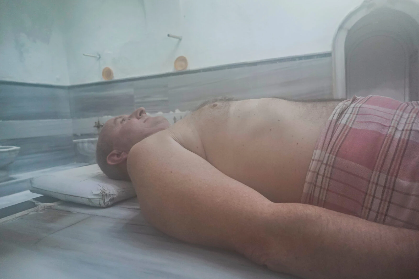 Man relaxing on a hot marble slab at a Turkish hamam in Istanbul.