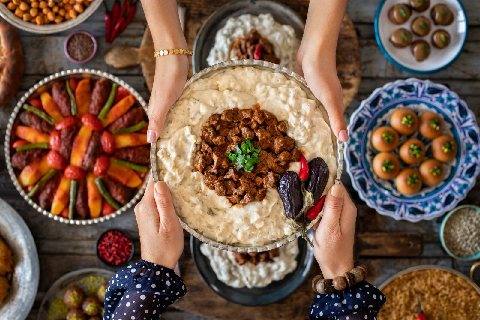 A bowl of Hunkar Begendi, a Turkish recipe with tender lamb stew served over a creamy eggplant puree, garnished with fresh herbs and chili peppers.