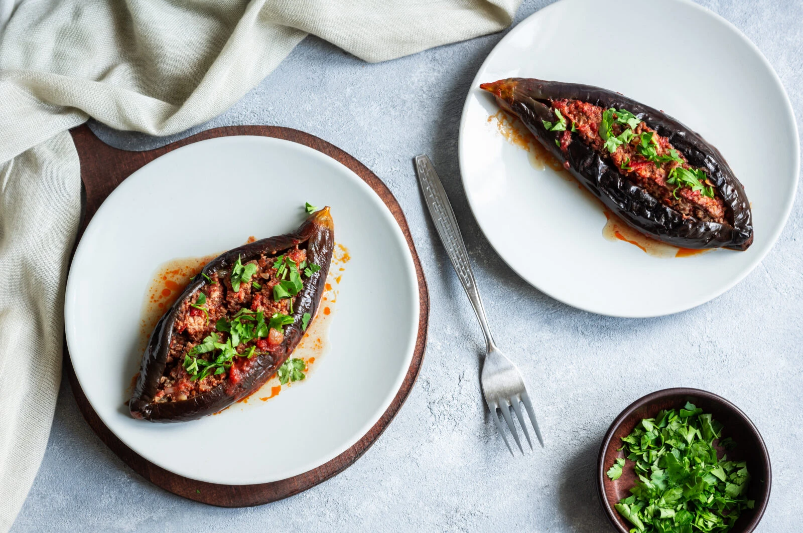 iftar meal's main dish: Two plates of Karniyarik, Turkish-style eggplants stuffed with ground meat and tomatoes, garnished with parsley.