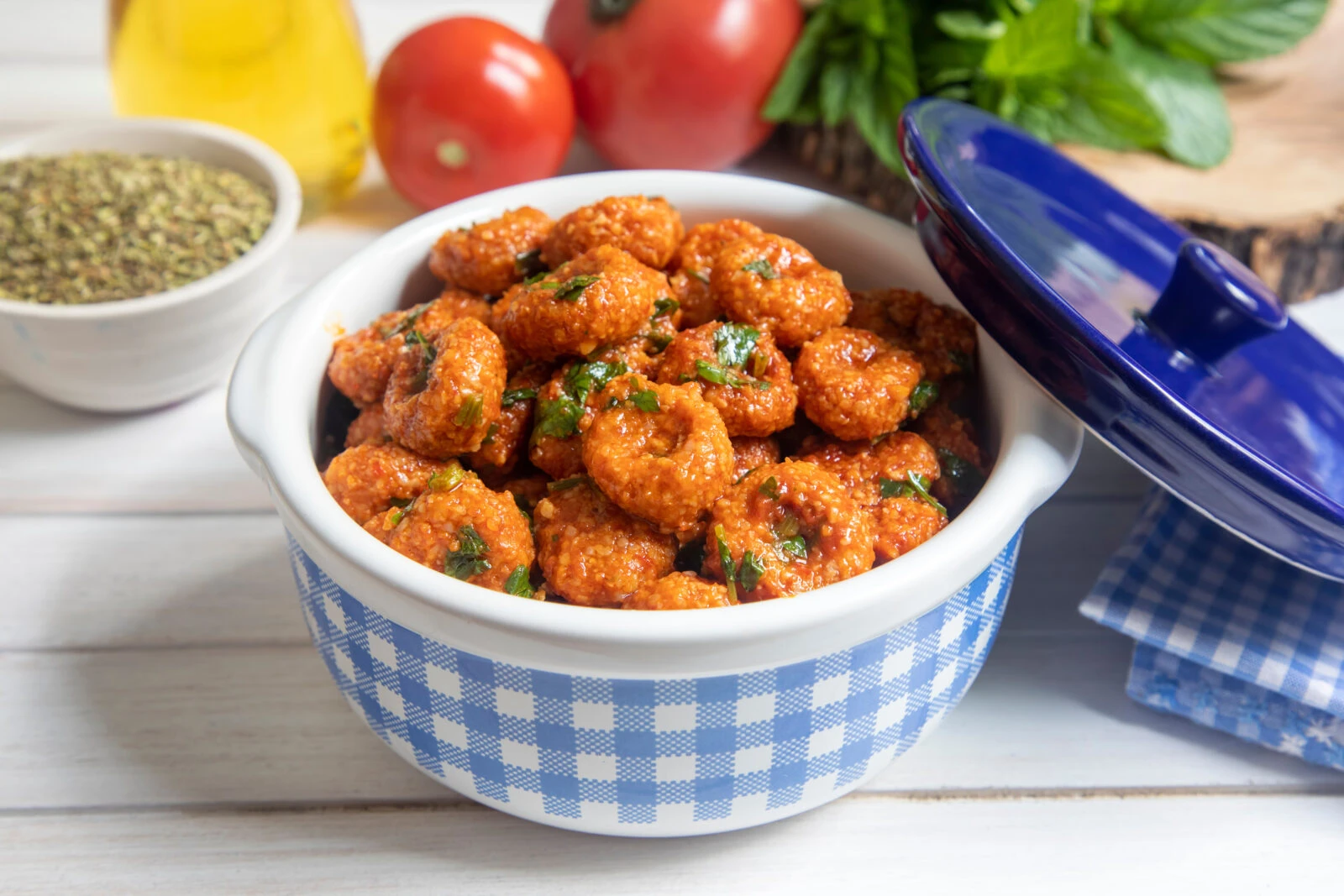 A bowl of Fellah Kofte, Turkish-style bulgur köfte covered in tomato sauce and garnished with fresh parsley.