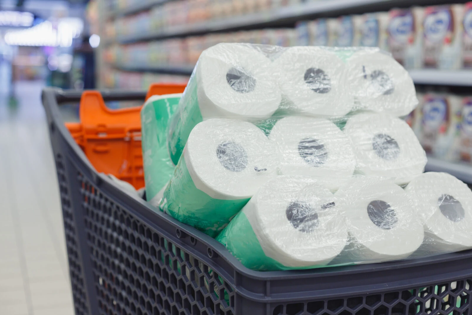 Shopping trolley full of toilet paper packs in supermarket