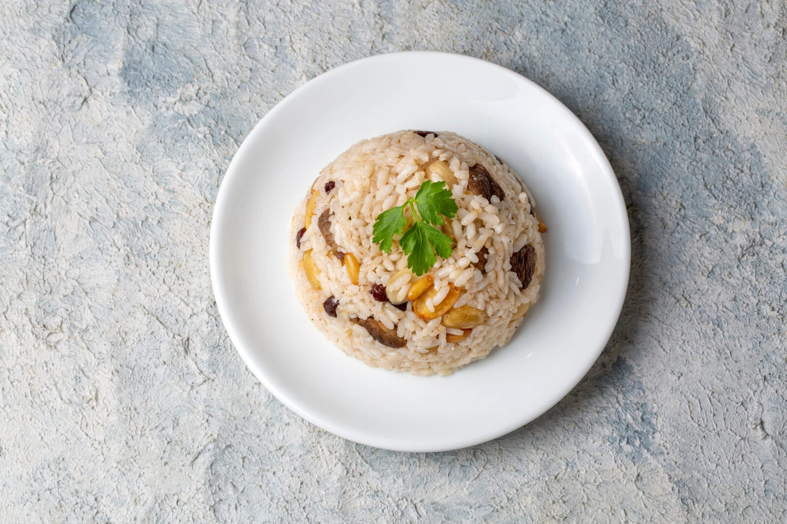 A plate of Turkish-style rice pilaf made with pine nuts and currants, served on a white dish.