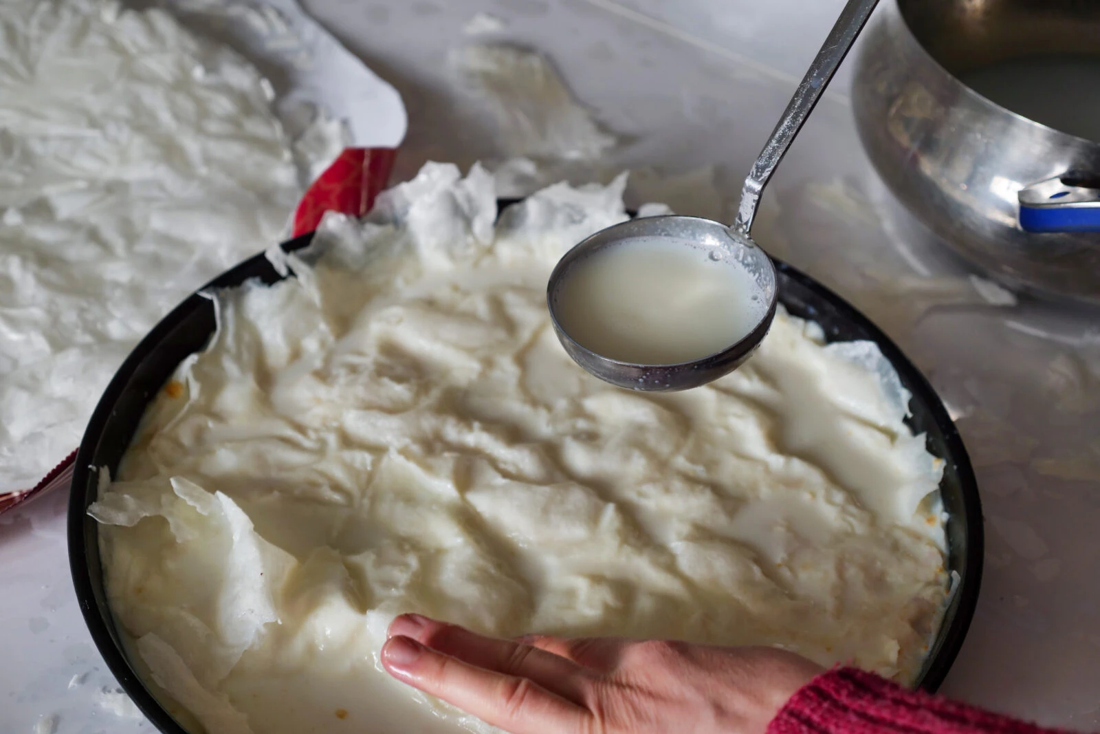 A woman preparing gullac with varak sheets resembling dough.