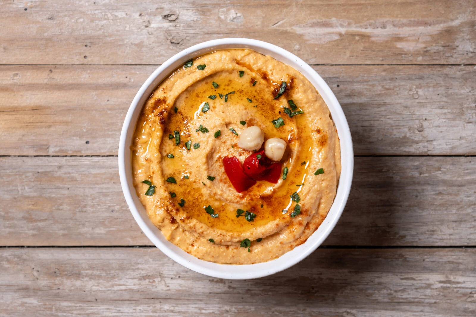 A bowl of smooth chickpea hummus drizzled with paprika-infused butter, a flavorful dish for iftar.