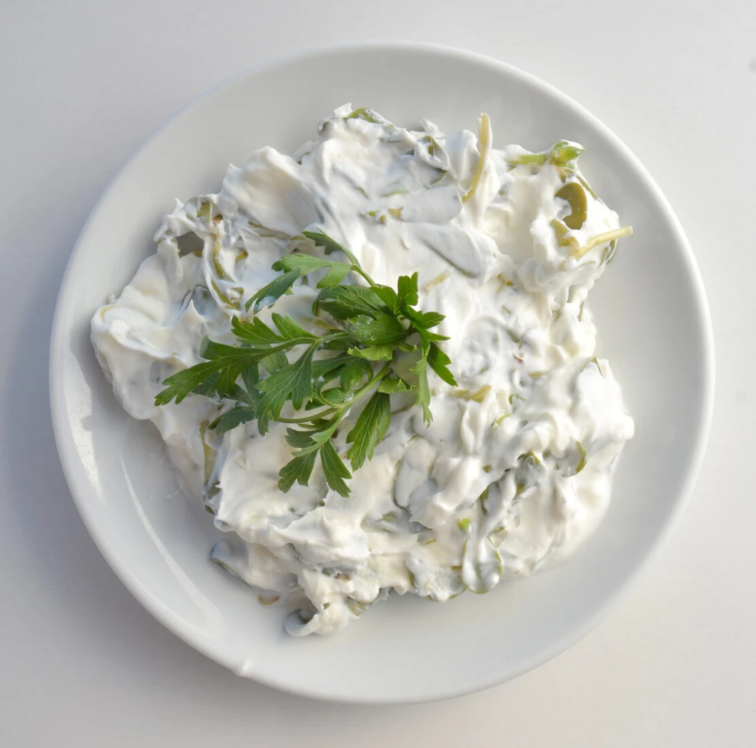 A plate of Turkish yogurt-based purslane salad garnished with fresh parsley, served on a white dish.