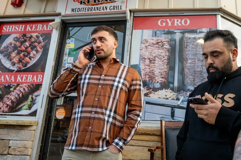 Muhammed Emanet talks on the phone with his father while approaching the Jersey Kebab restaurant.