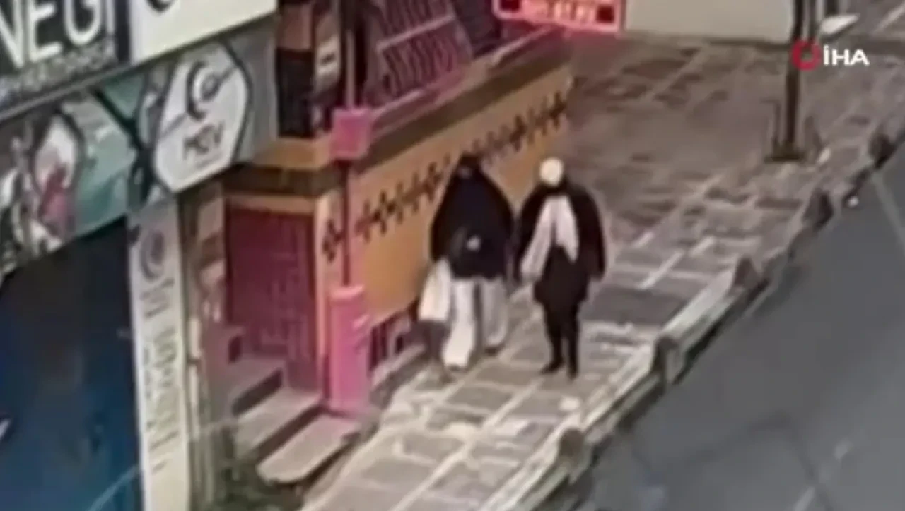 Two women wearing headscarves and long coats walking on a sidewalk in Istanbul, captured by CCTV.