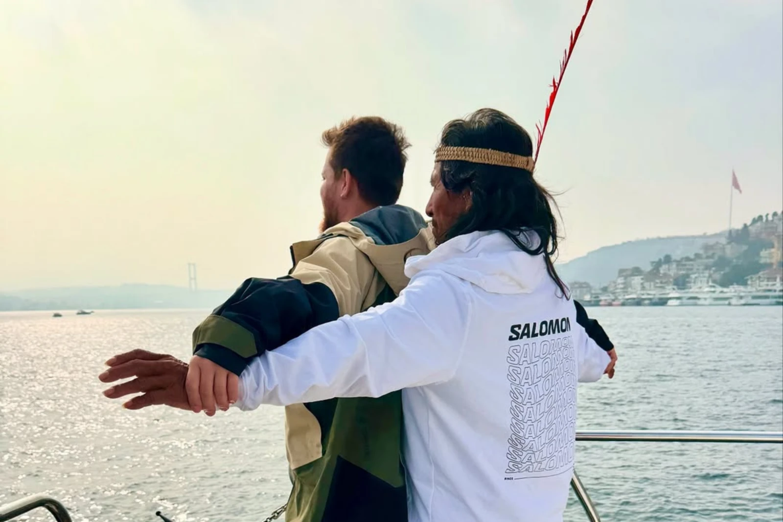 A Waorani man and Alper Rende recreate the famous Titanic pose on a boat in Türkiye, with the Bosphorus in the background.