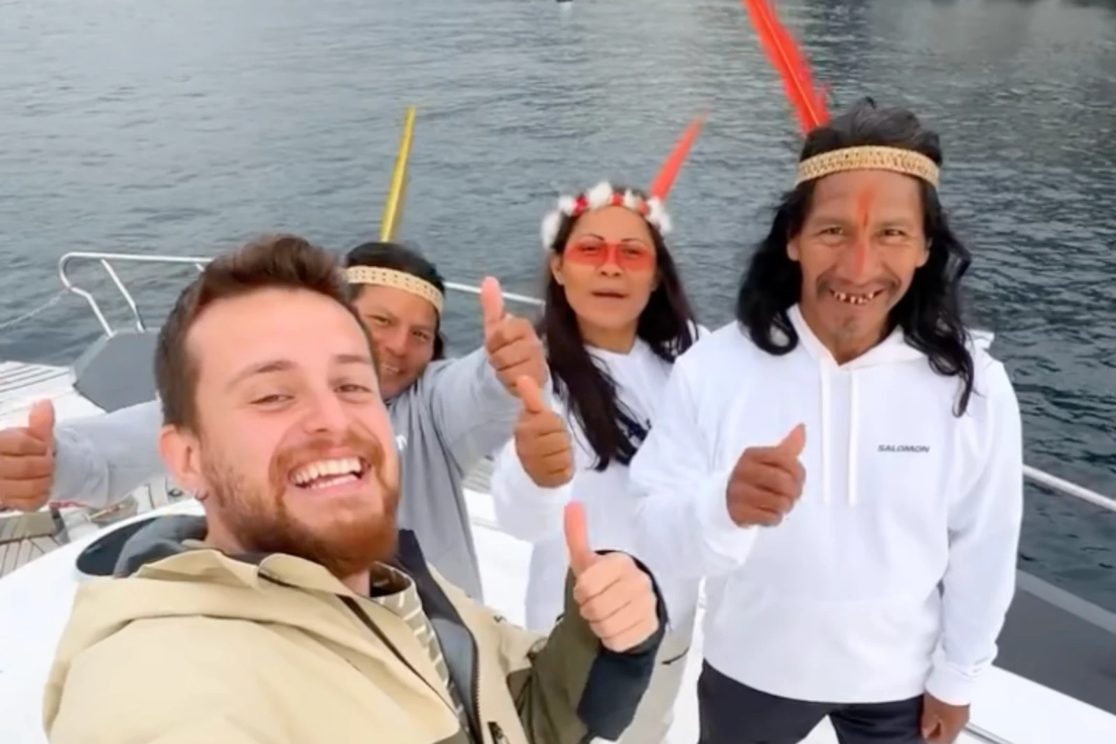 Alper Rende and the Waorani travelers smile and give a thumbs-up while taking a selfie on a boat in Türkiye.